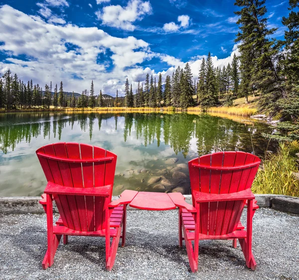 Dvě červené plastové židle na jezeře — Stock fotografie
