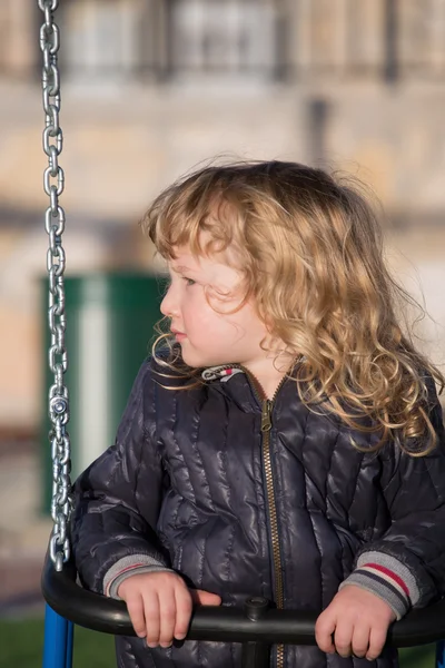 Niño pequeño en chaqueta negra en swing —  Fotos de Stock