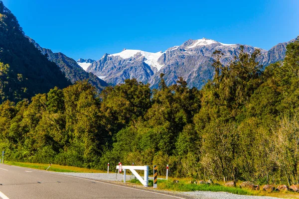 森林和山丘之间的高速公路 远处可见雪峰状的岩石 新西兰南岛 美好的一天 积极旅游和摄影旅游的概念 — 图库照片