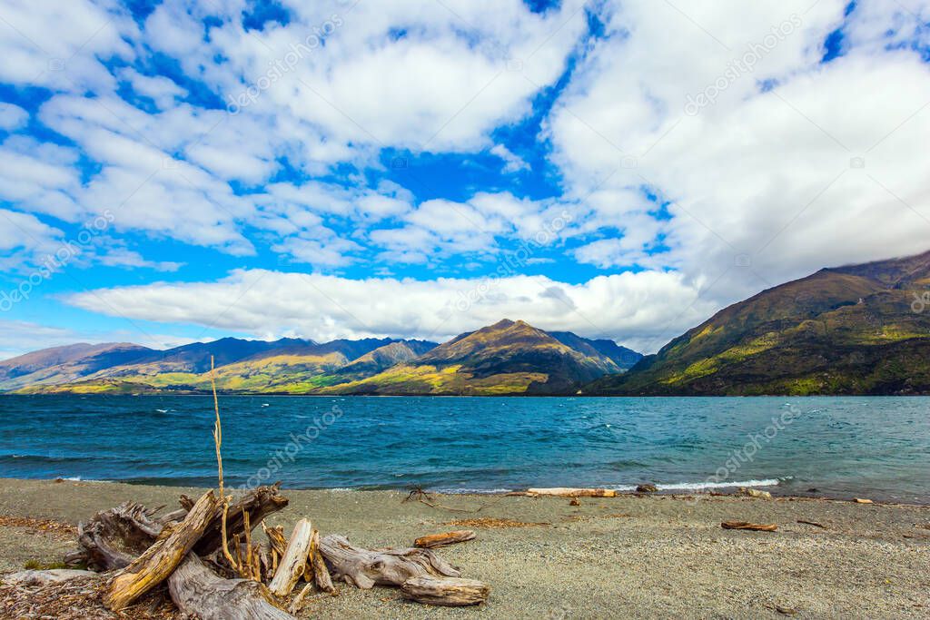 South Island. Clouds fly in the sky. Azure lake among the colorful mountains. The beautiful lake Wanaka in New Zealand. Concept of active, ecological and photo tourism