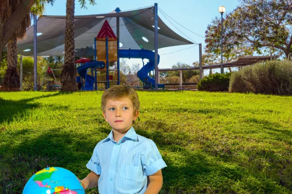 Kędzierzawy Niebieskooki Chłopiec Globusem Przytulny Plac Zabaw Dla Dzieci Wieloma — Zdjęcie stockowe