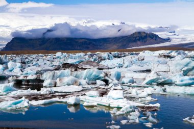 İzlanda. En büyük buzul gölü Jokulsaurloun. Buz bazı yerlerde siyah volkanik küllerle kaplıdır. Soğuk yaz sabahı. Kuzey ve fotoğraf turizmi kavramı