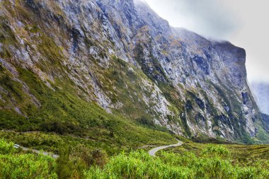 Görkemli sarp dağlar ve bulutlar ve sis içindeki soğuk uçurumlar. Milford Sound yolu. Yeni Zelanda 'nın Güney Adası. Aktif, aşırı ve fotoğraf turizmi kavramı
