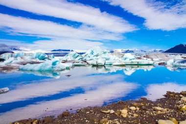 İzlanda. Bulutlar en büyük buzul gölü Jokulsaurloun 'un yumuşak sularına yansıdı. Beyaz ve mavi buzdağları ve buz kütleleri. Soğuk yaz sabahı. Kuzey ve fotoğraf turizmi kavramı