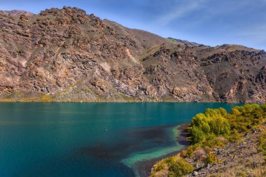 Mavi gökyüzü ve ışık bulutları. Cromwell şehrinin çevresi dağlar ve göller arasında. Yeni Zelanda Güney Alpleri. Ekolojik, manzara ve fotoğraf turizmi kavramı