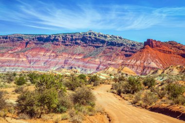Kırmızı kumtaşı toprak yolu. Paria Kanyonu-Vermilion Uçurumları Vahşi Doğa Bölgesi. Büyük kırmızı kumtaşı yamaçları, çeşitli hafif kayalardan çizgili. Ekstrem ve fotoğraf turizmi kavramı