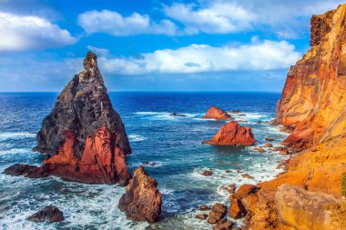 Atlantik 'teki ada. Adanın batı kıyısı. Keskin kırmızı kayalar, kaynayan turkuaz dalgalar. Kör edici gün ortası güneşi kayalık sahili aydınlatıyor. Aktif, ekolojik ve fotoğraf turizmi kavramı