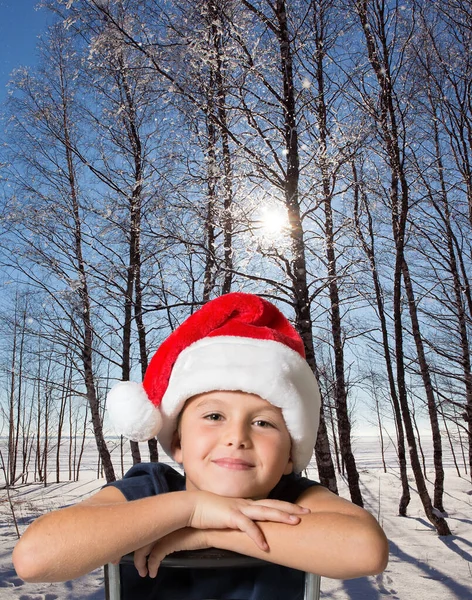 Kırmızı Noel Baba Şapkalı Yakışıklı Çocuk Zaferle Gülümsüyor Kış Ormanında — Stok fotoğraf
