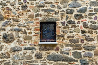 Toskana 'da bulutlu bir sonbahar günü. Montalcino 'nun küçük kasabası. Küçük bir pencerenin güzel dekor unsuru - metal pencere ızgarası. Bilişsel, aktif ve fotoğraf turizmi kavramı