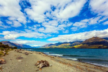 Güney Adası. Yeni Zelanda 'daki güzel Wanaka Gölü. Siren bulutları gökyüzünde uçar. Renkli dağların arasındaki gök mavisi göl. Etkin, ekolojik ve fotoğraf turizmi kavramı