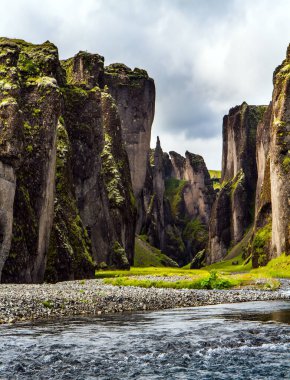 Buzul suyu olan nehir tuhaf uçurumlar arasında akar. İzlanda 'nın en güzel ve gizemli kanyonu Fyadrarglyufur. Bulutlu bir yaz günü. Aktif, eko ve fotoğraf turizmi kavramı