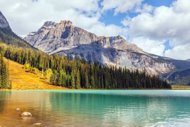 Rocky Dağları 'nda güneşli soğuk bir gün. Muhteşem Zümrüt Göl. Kozalaklı orman ve dağ zirveleri gölü masmavi suyla çevreler. Ekolojik ve fotoğraf turizmi kavramı