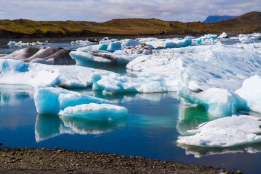 İzlanda. Skaftafell Park 'taki Jokulsaurloun gölü. Temmuz 'da soğuk bir gün. Suya yansıyan beyaz ve mavi buzdağları ve buz kütleleri. Ekstrem, kuzey ve fotoğraf turizmi kavramı