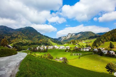 Dağ vadisinde küçük bir köy. Slovenya 'ya git. Resimli Julian Alps. Güzel bir sonbahar günü. Hoş bir pastoral. Bir dağ vadisinde yeşil çimenler. 