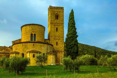 San Antimo 'nun antik ortaçağ muhteşem manastırı. Resimli Toskana usulü. Uzun ince selvi manastırın etrafındaki çayırı süslüyor. Aktif, kırsal ve fotoğraf turizmi kavramı