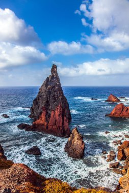 Atlantik 'teki ada. Keskin kırmızı kayalar, kaynayan turkuaz dalgalar. Kör edici gün ortası güneşi kayalık sahili aydınlatıyor. Aktif, ekolojik ve fotoğraf turizmi kavramı