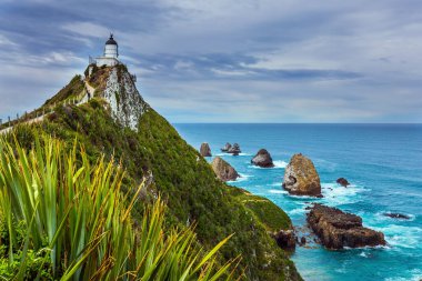 Pasifik Okyanusu 'nun pitoresk sahili. Nugget Point Deniz Feneri, Nugget Burnu 'nda. Güney Adası, Yeni Zelanda. Aktif, çevresel ve fotoğraf turizmi kavramı