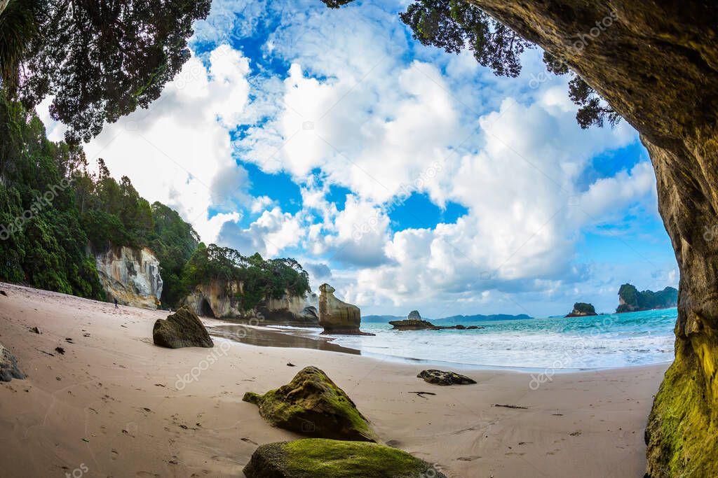 The concept of exotic, ecological and photo tourism. Pacific Coast of New Zealand. The magnificent fantastic Cathedral Cave on the sandy beach. Ocean inflow begins at sunset 