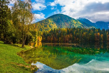  Suyun yeşil yüzeyi bulutlu gökyüzünü yansıtır. Kuzey İtalya 'daki sessiz göl, Lago de Fusine. Kültürel ve ekolojik turizm kavramı