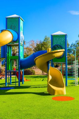 Parlak, güneşli bir sabah. Değişik renklerde eğlencelerle dolu güvenli ve rahat çocuk parkı. Çocuklar için açık güneş çimleri. Çocukların fiziksel ve zihinsel gelişimi kavramı