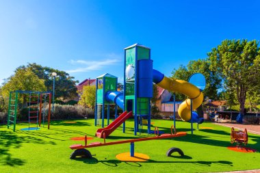  Rahat ve güvenli çocuk parkı. Renkli sürüş çeşitleri. Çocuklar için açık hava güneşli çimenler. Parlak, güneşli bir sabah. Çocukların fiziksel ve zihinsel gelişimi kavramı
