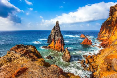 Kör edici gün ortası güneşi kayalık sahili aydınlatıyor. Keskin kırmızı kayalar, kaynayan turkuaz dalgalar. Madeira Atlantik 'te büyülü bir adadır. Aktif, ekolojik ve fotoğraf turizmi kavramı