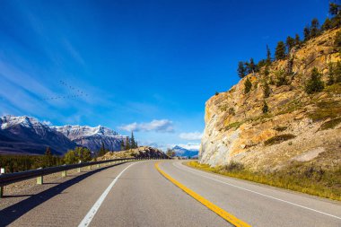 Kanada Kayalıkları 'nda muhteşem bir Kızılderili yazı. Rocky Dağları 'nın keskin zirveleri mavi gökyüzüne karşı açıkça görülebilir. Asfalt karayolu Abraham Gölü 'ne çıkıyor.