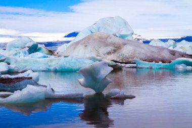 Garip buzdağları ve yüzen buz kütleleri gölün yumuşak soğuk suyuna yansıyor. Soğuk, berrak Temmuz günü. Jokulsaurloun gölü. İzlanda. Eko, kuzey ve fotoğraf turizmi kavramı