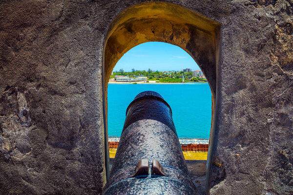 Loophole and gun in the thick ancient walls. Kenya. Fort Jesus -  medieval fortification in Mombasa. The concept of historical, educational and photo tourism