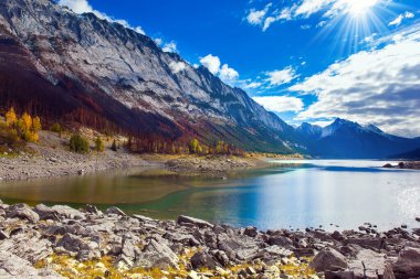 Kanada, Alberta, Jasper Park. Lake Medicine 'de. Medicine Gölü 'nün altında dünyadaki en uzun yeraltı nehir sistemi var. Harika bir sonbahar günü. Güneş karla kaplı dağları aydınlatıyor.