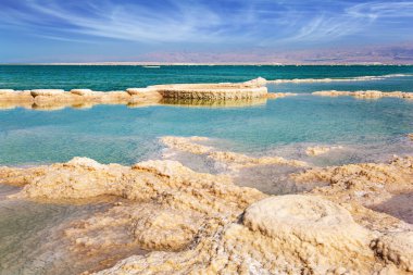 Buharlaşmış tuz, suda tuhaf desenler oluşturur. Ölü Deniz 'in İsrail kıyıları. Rüzgarlı bir bahar günü. Siren bulutları mavi gökyüzünde uçar