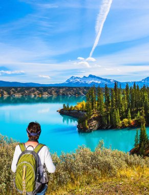 Kanada 'nın Rocky Dağları' nda Abraham Lake. Aktif, ekolojik ve fotoğraf turizmi kavramı. Büyük bir sırt çantası olan orta yaşlı bir kadın göle hayran.