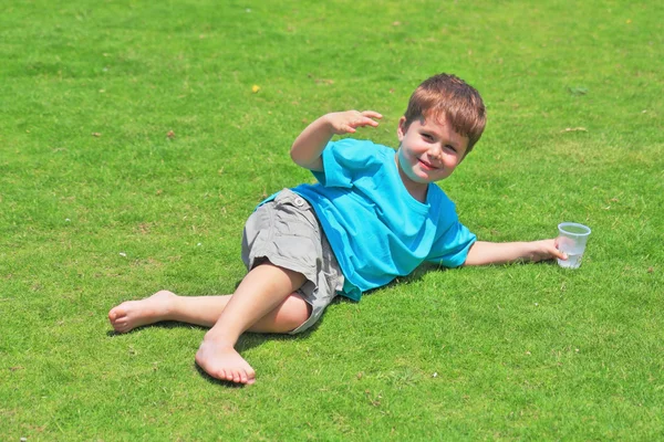 Boy with pleasure laying on lawn — Stock Photo, Image
