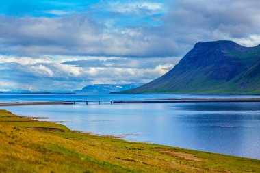 The cold fjord reflects clouds