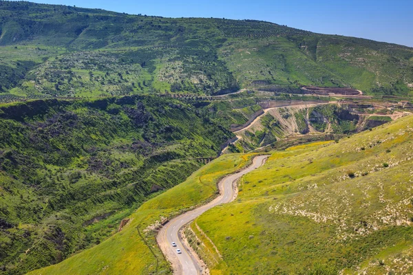 Serpentine road winds through the green hills. — ストック写真