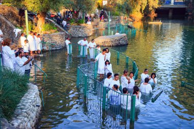  YARDENIT, ISRAEL - 21 HAZİRAN 2012: Beyaz vaftiz gömleklerine inanan bir grup Ürdün Nehri 'nin sularına girer. Soğuk güneşli Ocak günü.