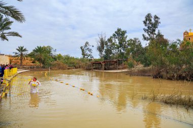 QASR EL YAHUD, ISRAEL - 2 Mart 2020: kadın sudan çıkar. Rahip vaftiz ayinini yönetir. İsa 'nın vaftiz edildiği yer Ürdün Nehri üzerinde tarihi bir yer.. 