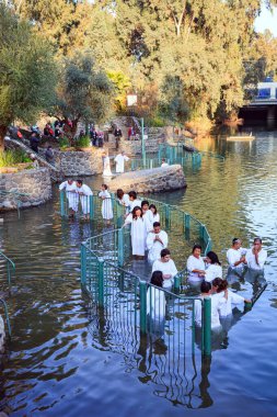 YARDENIT, ISRAEL - 21 HAZİRAN 2012: Beyaz vaftiz gömleklerine inanan bir grup Ürdün Nehri 'nin sularına girer. Yardenit, Ürdün Nehri 'nin Celile Denizi' nden çıkış noktasıdır.. 