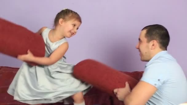 性格开朗的父亲和女儿战斗在沙发上的枕头. — 图库视频影像