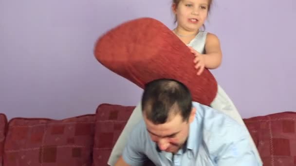 Cheerful father and daughter fighting pillows on couch. — Stock Video