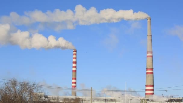 Thermische centrale in zonnige koude dag. Industriële rook uit de leidingen tegen blauwe hemel. — Stockvideo