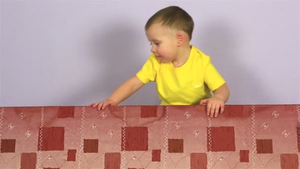 Glad glad liten pojke spelar och hoppa på soffan. — Stockvideo