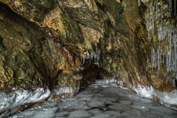 Flerfärgad sten grotta i klippan med istappar. — Stockfoto