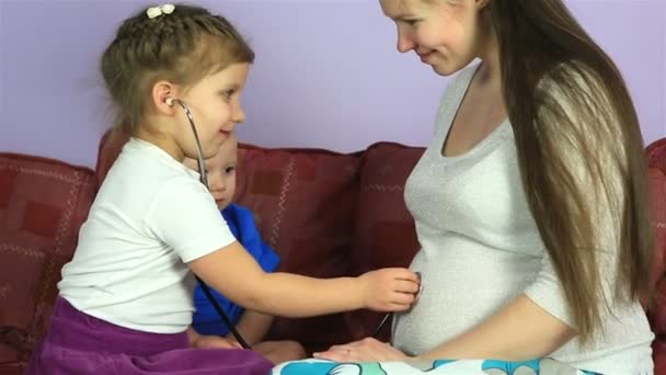 Los niños pequeños escuchan a su hermano en el estómago de la madre embarazada . — Vídeos de Stock