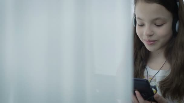 漂亮的小女孩，戴着耳机在平板电脑上的搞笑视频 — 图库视频影像