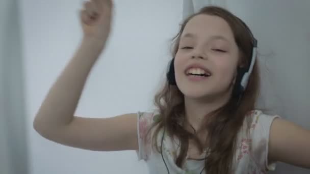 Hermosa niña en auriculares cantando canción emocionalmente y bailando — Vídeo de stock