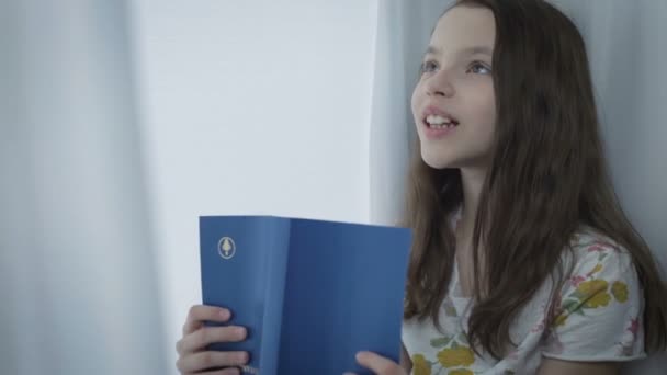 Hermosa niña aprende un poema por ventana . — Vídeos de Stock