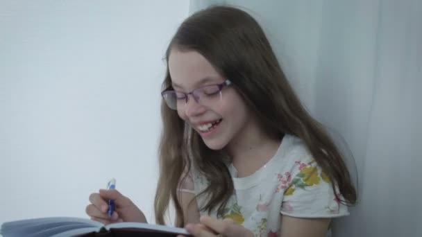 Emotional little girl in glasses laughing at window. — Stock Video