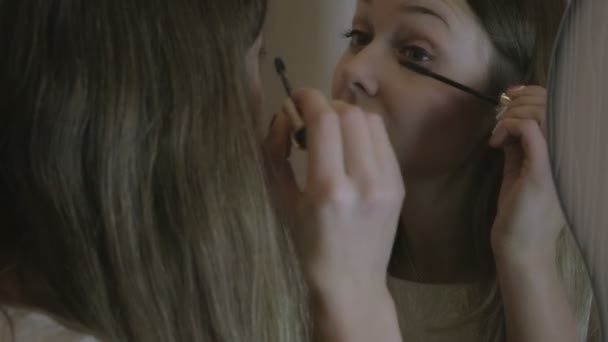美しい少女は鏡の前でまつげのマスカラーを塗料します。. — ストック動画