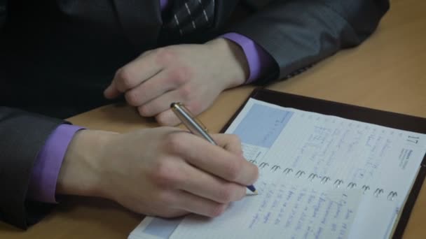 Businessman working in office. He wrote in the diary. — Stock Video